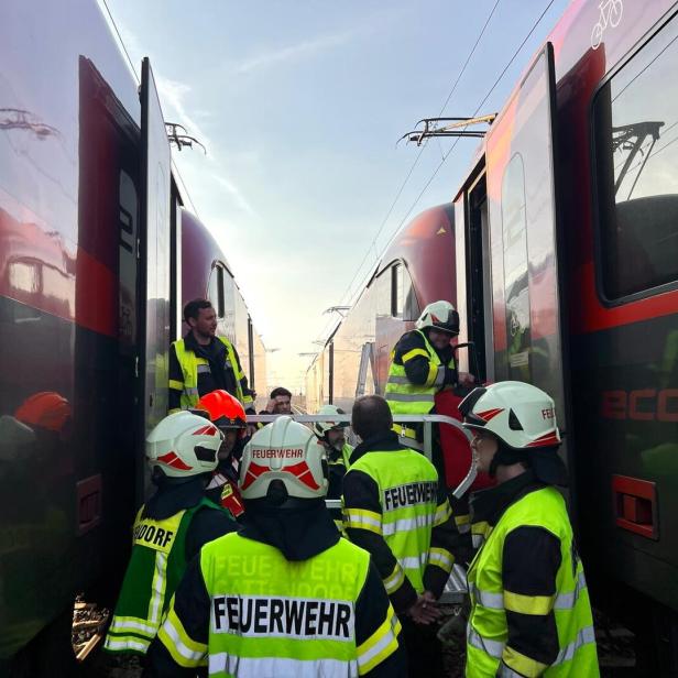 Mehrere Feuerwehrleute stehen zwischen zwei haltenden Zügen und unterstützen bei einer Evakuierung.