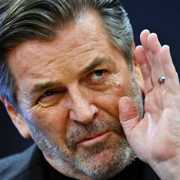 Thomas Anders mit grau meliertem Haar hält die Hand hoch.