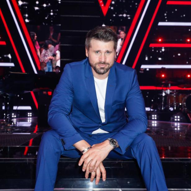 Thore Schölermann lächelt im blauen Anzug auf der Bühne.