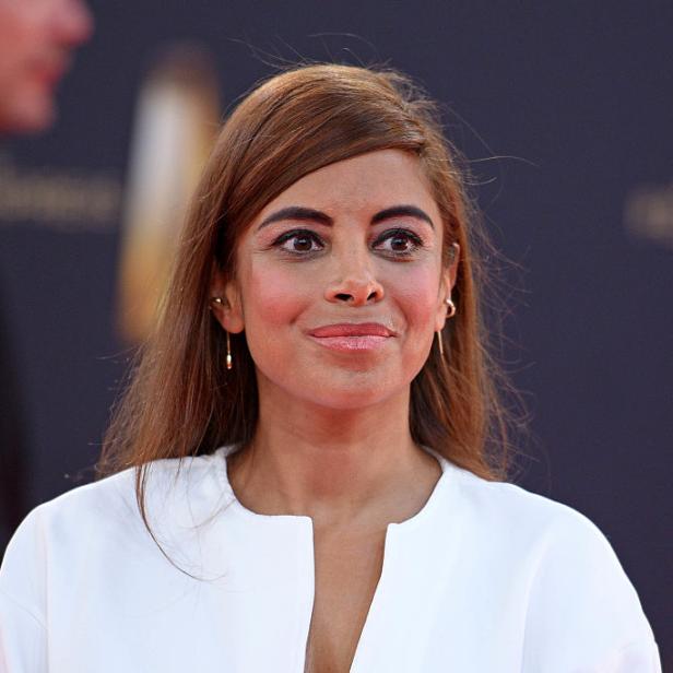 Collien Ulmen in einem weißen Oberteil vor unscharfem Hintergrund.