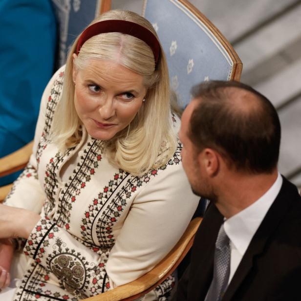 Die blonde Mette-Marit mit Haarreif spricht mit Haakon im Anzug.