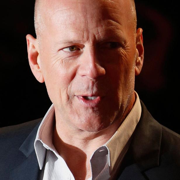 Bruce Willis mit Anzug blickt aufmerksam zur Seite.
