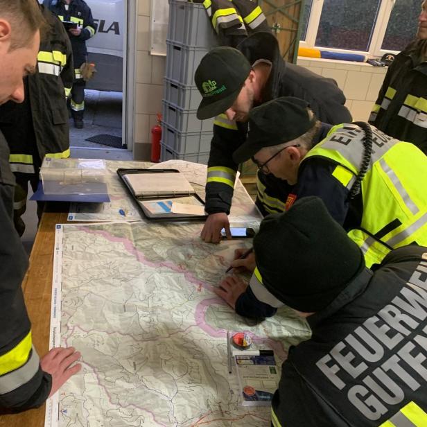 Einsatzkräfte der Feuerwehren Rohr im Gebirge und Gutenstein besprechen an einer großen Karte das Suchgebiet für die vermisste Person.