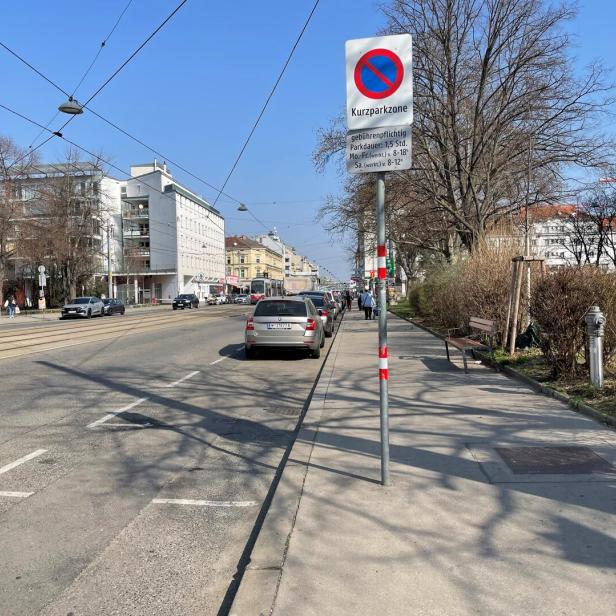 Eine Straße in Wien mit geparkten Autos und einem Kurzparkzonen-Schild.