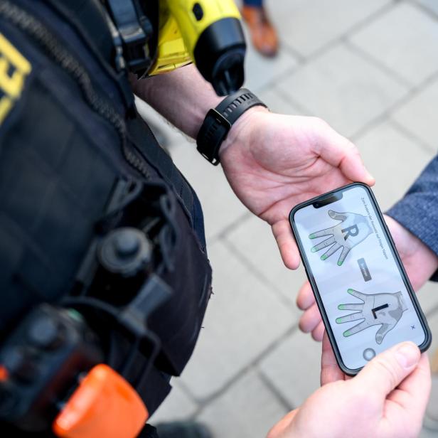Polizist scannt Fingerabdrücke mit einem Smartphone auf offener Straße.
