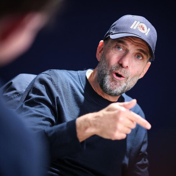 Jürgen Klopp trägt eine dunkle Kappe und einen Pullover, während er gestikulierend in einem Gespräch spricht.