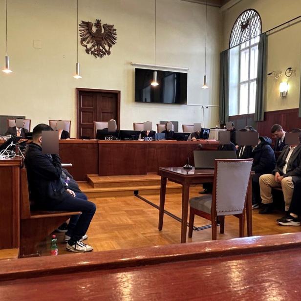 Angeklagte, Verteidiger, Richter und Dolmetsch im Gerichtssaal.