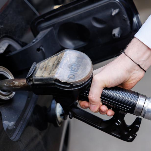 Eine Person tankt ein Auto mit einer Dieselpistole an einer Zapfsäule.