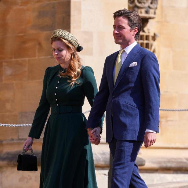 Prinzessin Beatrice im grünen Kleid mit Hut und Handtasche geht Hand in Hand mit einem Mann im blauen Anzug auf einem Gehweg.