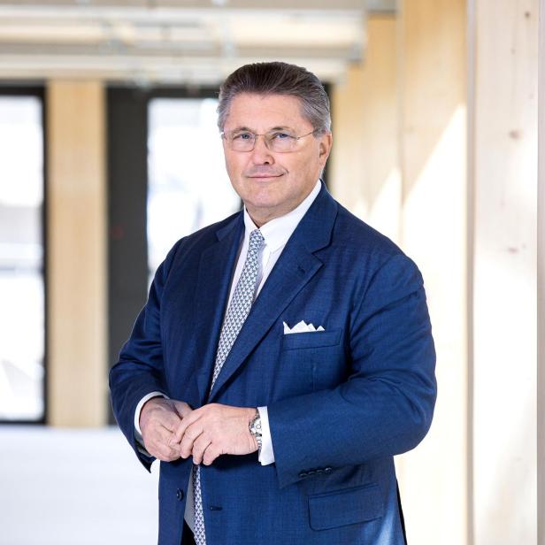 Mann im blauen Anzug steht in modernem, lichtdurchflutetem Bürogebäude.