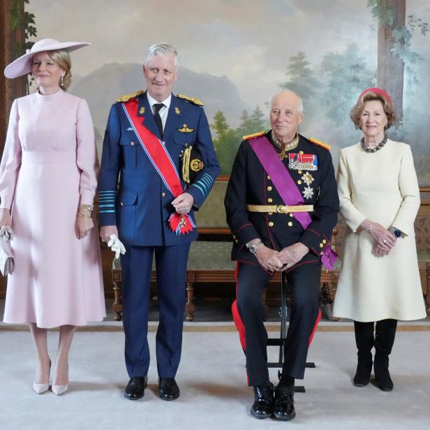 Königin Sonja und König Harald V. mit König Philippe und Königin Mathilde. Alle sind elegant gekleidet. Harald sitzt, die anderen Personen stehen.