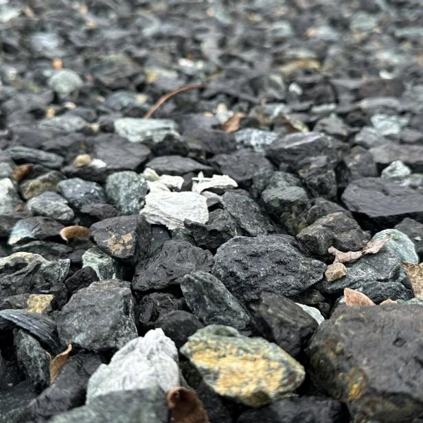 Viele kleine, unterschiedlich gefärbte Steine liegen dicht nebeneinander auf dem Boden.