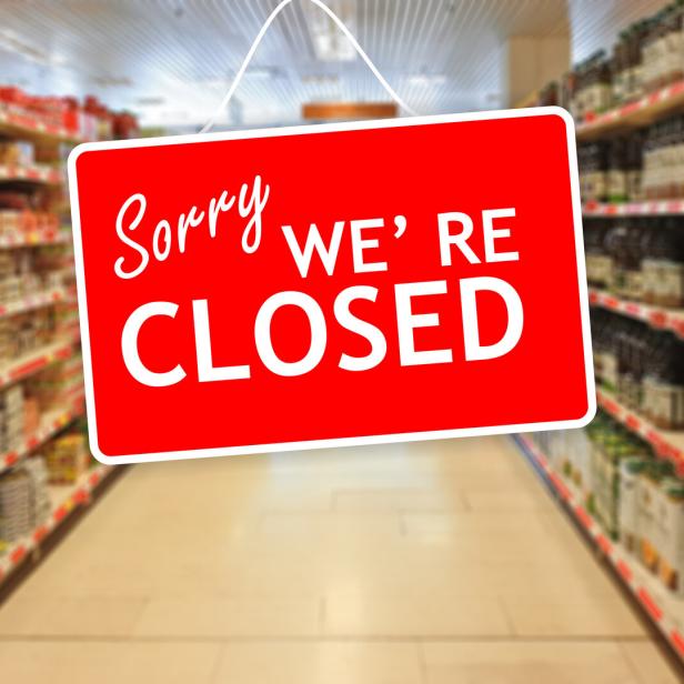 Ein rotes Schild mit der Aufschrift "Sorry, we're closed" hängt in einem Supermarktgang.
