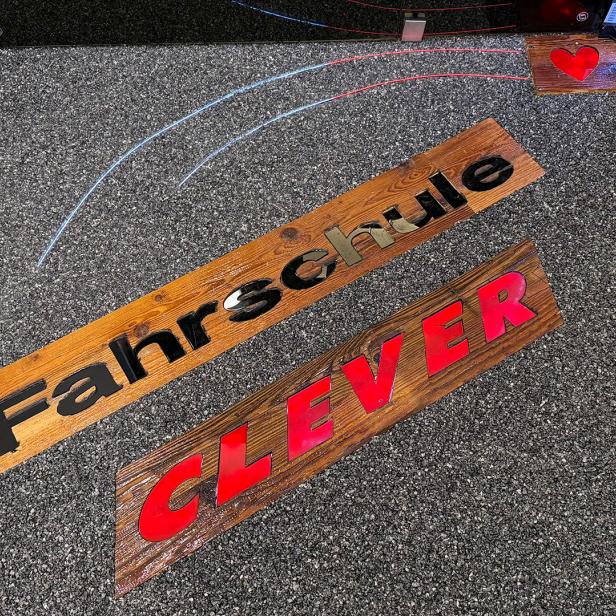 Eine Fußmatte liegt auf einem Fließenboden vor einer Eingangstüre mit der Aufschrift "Fahrschule Clever".