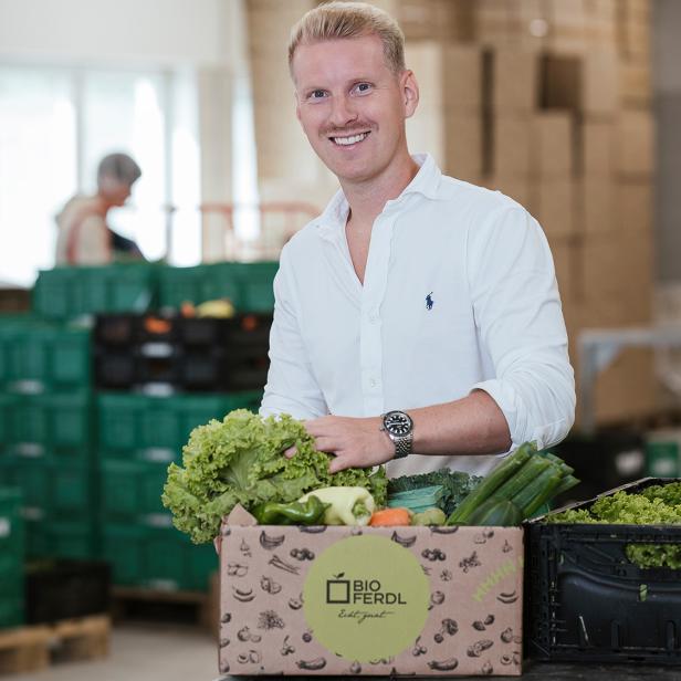 Ein blonder Mann in einem weißen Hemd mit einem Obstkorb. 