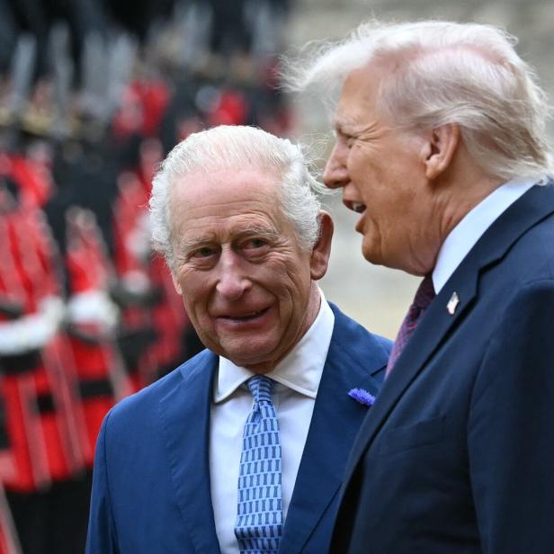 König Charles und Donald Trump unterhalten sich, im Hintergrund sind Soldaten in roten Uniformen zu sehen.