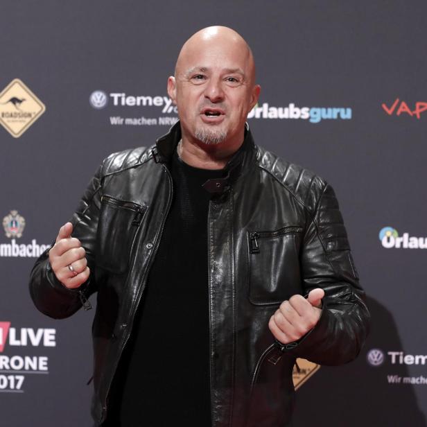 Detlef Steves posiert auf dem roten Teppich der 1LIVE Krone 2017 in schwarzer Lederjacke vor Sponsoren-Logos.