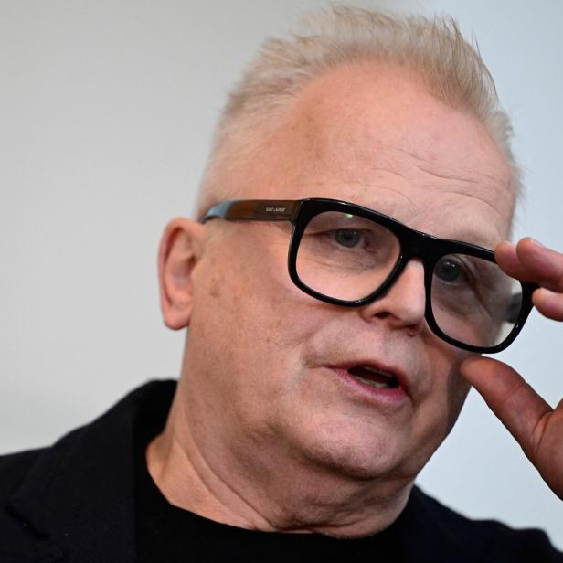 Herbert Grönemeyer mit hellen Haaren und schwarzer Jacke hält seine schwarze Brille fest.