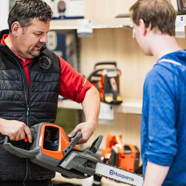 Ein Mann zeigt einem jüngeren Mann eine Schneidemaschine 