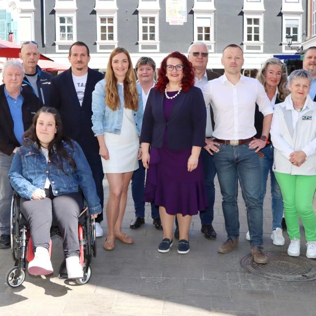 Eine Gruppe von etwa zwölf Personen posiert im Freien vor einem Gebäude.