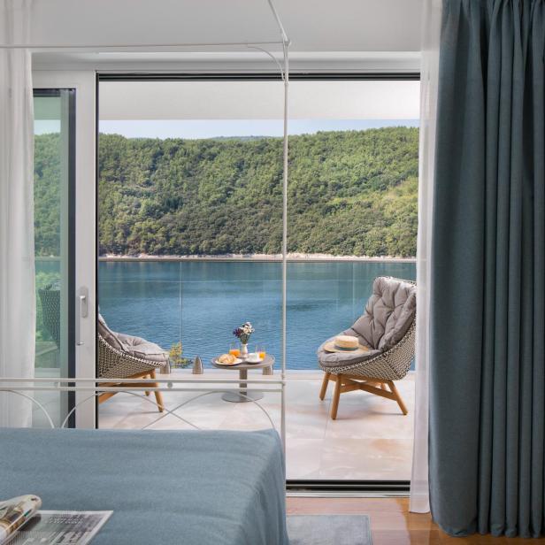 Blick aus einem modernen Schlafzimmer auf eine Terrasse mit Sitzmöbeln und Meerblick in Istrien.