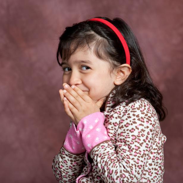 Ein Mädchen kichert und greift sich zum Mund.