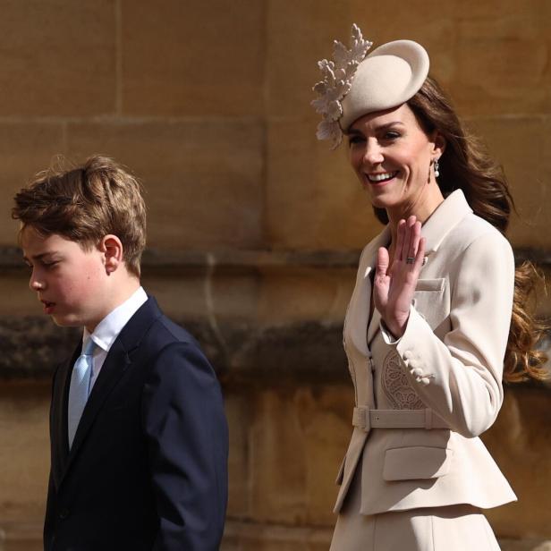 Prinzessin Kate mit Hut winkt, während Prinz George im Anzug neben ihr geht.