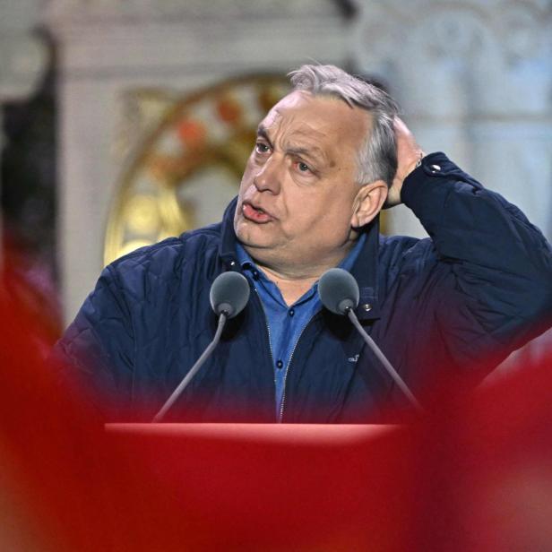 Viktor Orbán steht am Rednerpult und fährt sich nachdenklich durch die Haare.