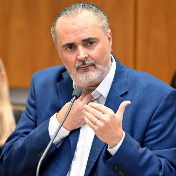 Doskozil spricht vor einem Mikrofon, mit zwei Personen im Hintergrund.