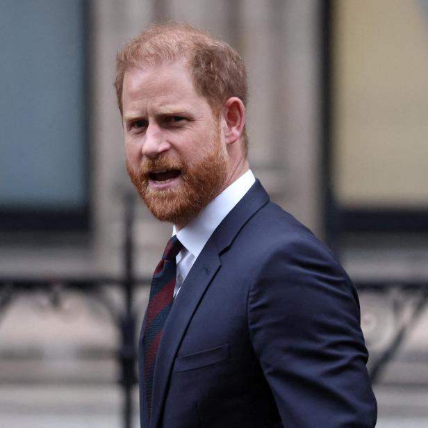 Prinz Harry, mit Bart und Anzug, blickt zur Seite.