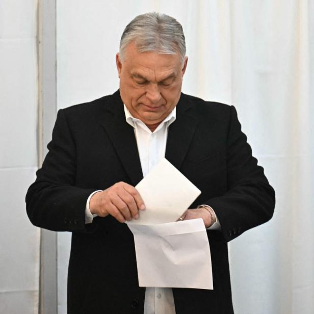 Viktor Orban steckt einen Zettel in einen Umschlag.