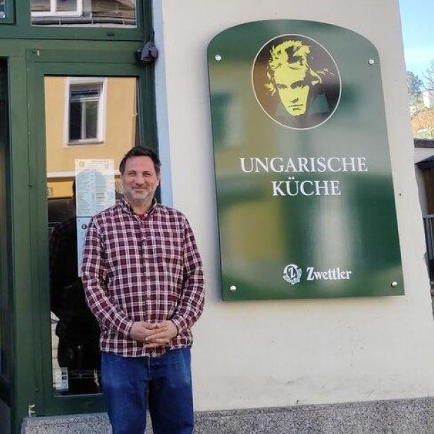 Ein Mann steht vor dem Restaurant "Ungarische Küche" mit einem Schild von Zwettler.