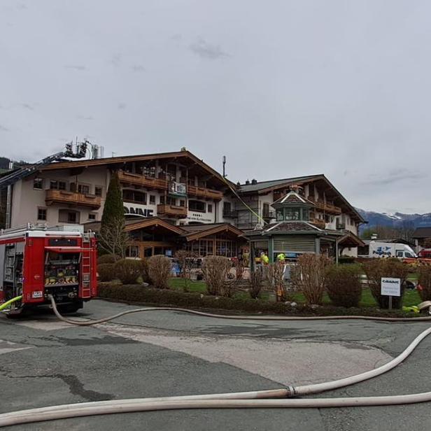 Feuerwehreinsatz mit Löschfahrzeugen und Schläuchen vor einem Hotel in Tirol.