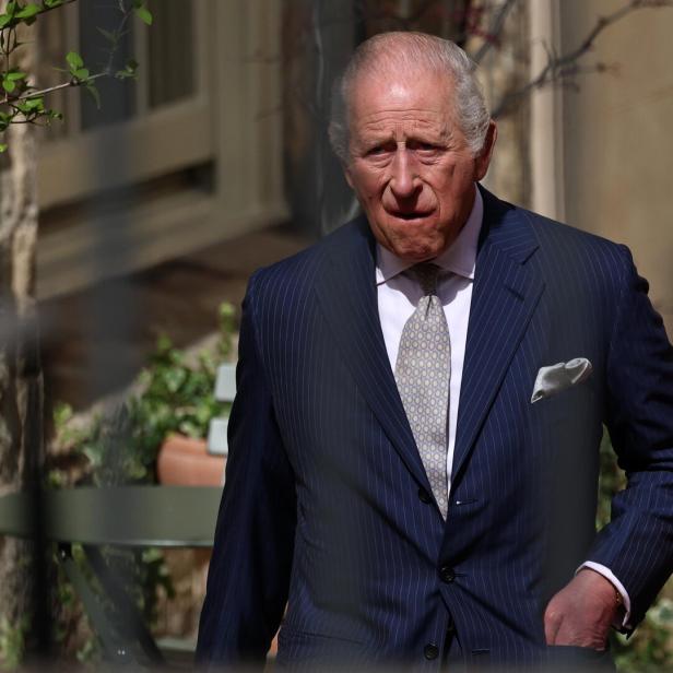 König Charles III. trägt einen gestreiften Anzug und eine Krawatte im Freien.