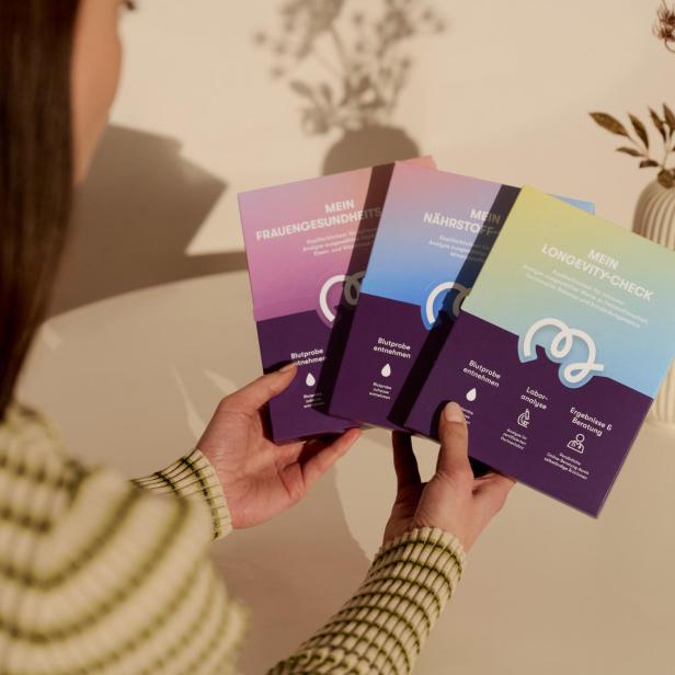 Eine Frau hält Testkits von Bipa und MavieMe in der Hand. 