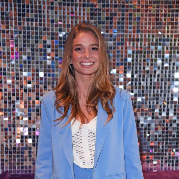 Lola Weippert steht lächelnd vor einer glitzernden Wand, obwohl sie aktuell eine schwere Lebenskrise durchmacht.