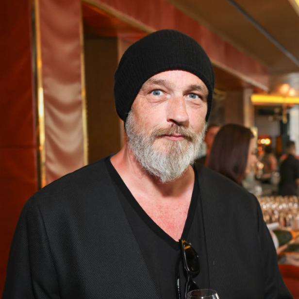Torsten Sträter mit schwarzer Mütze und Glas Wein in der Hand bei einer Veranstaltung.