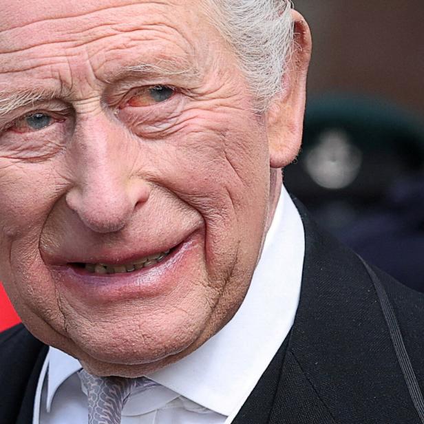 Nahaufnahme von König Charles im Anzug mit Krawatte, der lächelt.