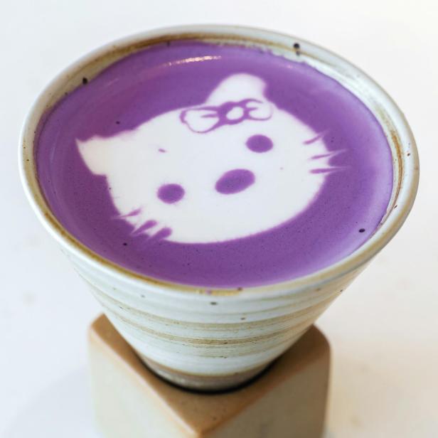 Violettes Milchgetränk mit einem Katzenmotiv im Milchschaum