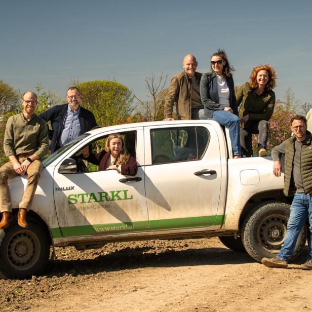 Mehrere Mitglieder der Familie Starkl posieren gemeinsam auf und neben einem Firmenfahrzeug im Grünen anlässlich des 110-jährigen Jubiläums der Gärtnerei.