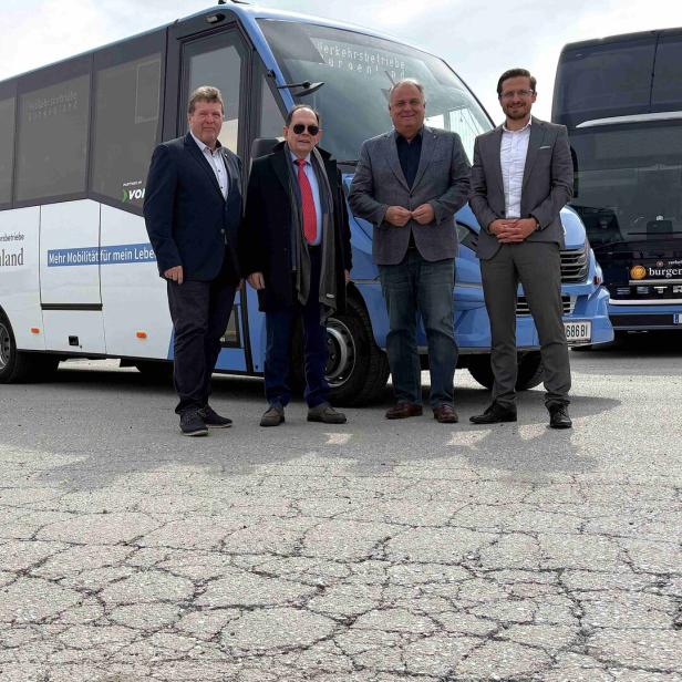 Vier Männer in Anzügen stehen vor drei blauen Bussen mit der Aufschrift „burgenland“ auf einem asphaltierten Platz.