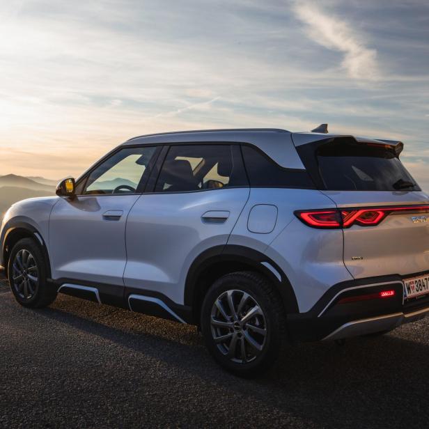 BYD Atto 2 DM-i von links hinten vor Bergkulisse bei Sonnenuntergang.