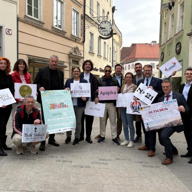 Die Gründerinnen und Gründer stehen in der Kremser Fußgängerzone, halten Plakate mit ihren Firmen in Händen und lächeln in die Kamera.