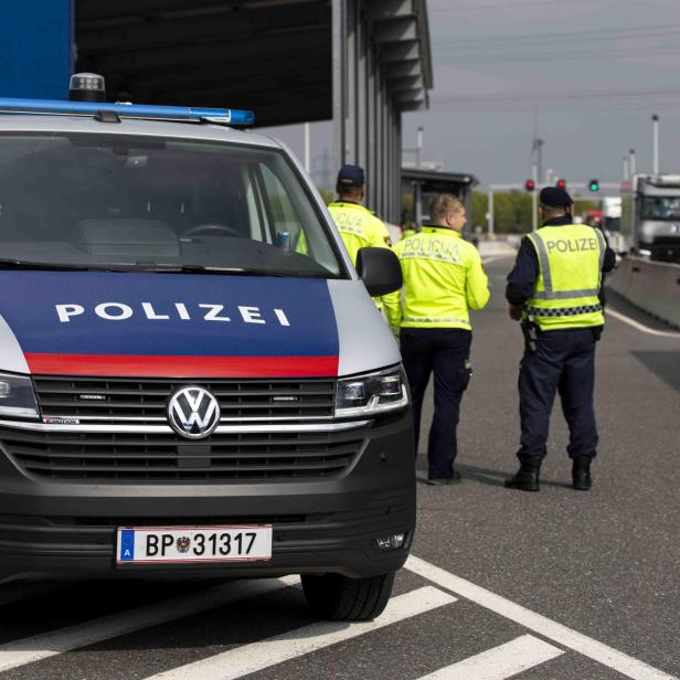 Polizeifahrzeug und mehrere Polizisten bei einer Verkehrskontrolle auf einer Autobahn.