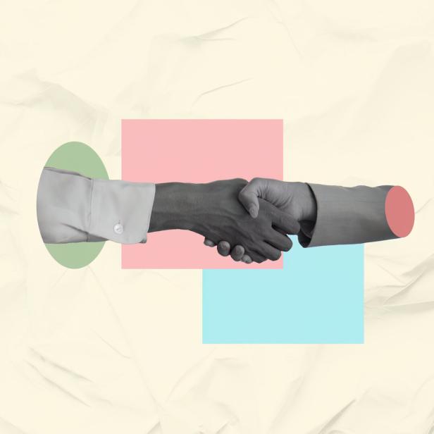 Professional handshake between a light skinned woman and a dark-skinned man in a corporate setting, fostering collaboration