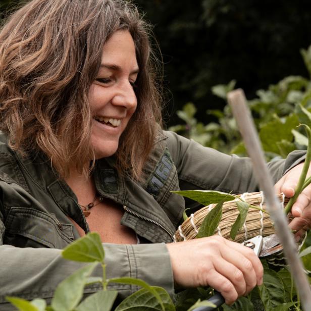 Eine Frau schneidet etwas im Garten ab 