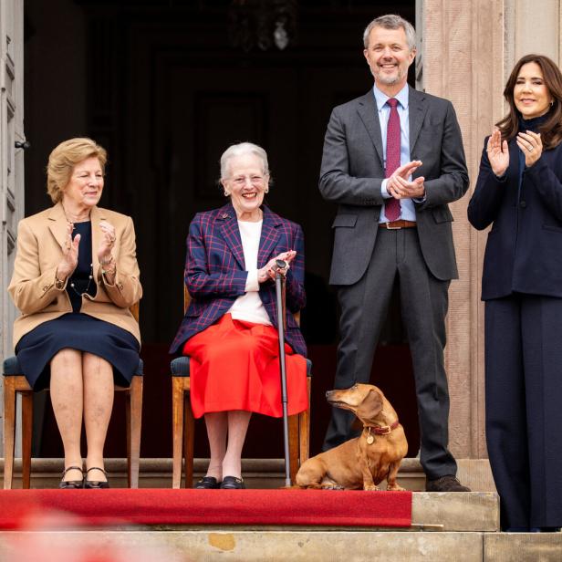 Königin Margrethe, Familie und ein Dackel stehen auf einer Treppe und klatschen.
