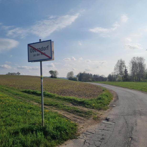 Ortsschild von Oberndorf an der Melk am Rand eines Feldes mit angrenzender Landstraße.