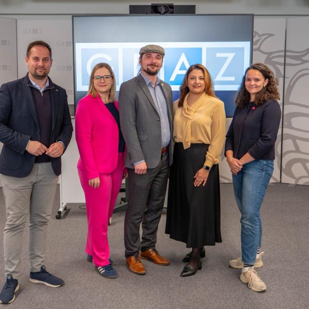 Fünf Personen posieren vor einem Bildschirm mit dem Schriftzug "GRAZ".
