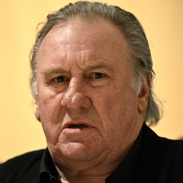 Nahaufnahme von Gérard Depardieu vor einem hellgelben Hintergrund.